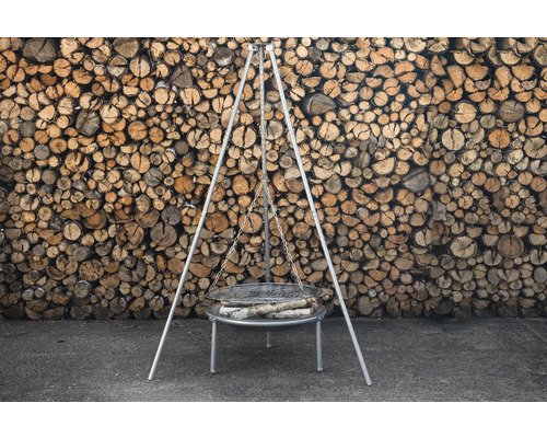 Grillstativ med ved framför trävägg