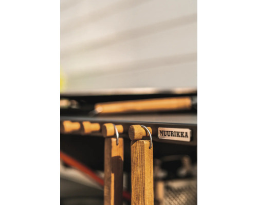 Muurikka logotyp bredvid grilltillbehör med trähandtag