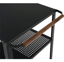 Detaljvy av en svart serveringsvagn med trähandtag och perforerade hyllor