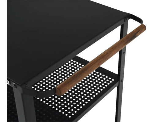 Detaljvy av en svart serveringsvagn med trähandtag och perforerade hyllor