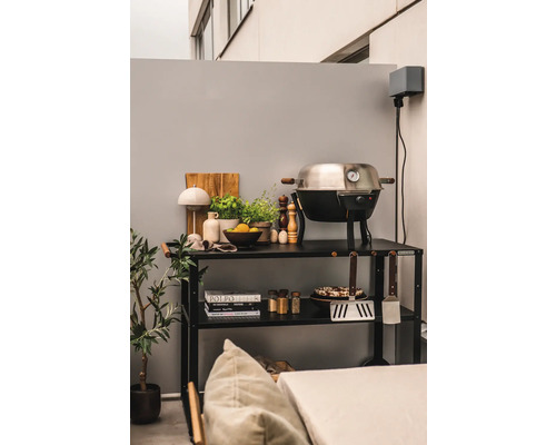 Uteplats med grill, grillverktyg och örter på en svart hylla