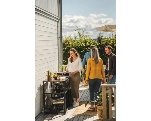 Scen av en grillfest med grillvagn och flera personer utomhus.