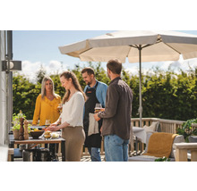 Grupp av människor grillar utomhus under ett parasoll