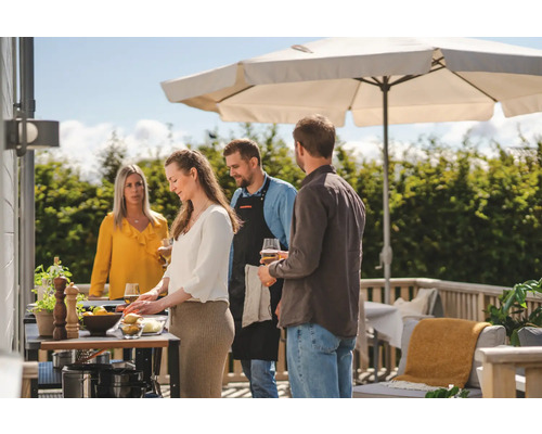 Grupp av människor grillar utomhus under ett parasoll