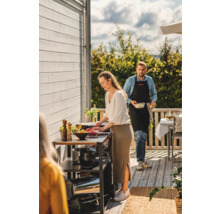 Personer som förbereder mat på en utomhusgrillstation.