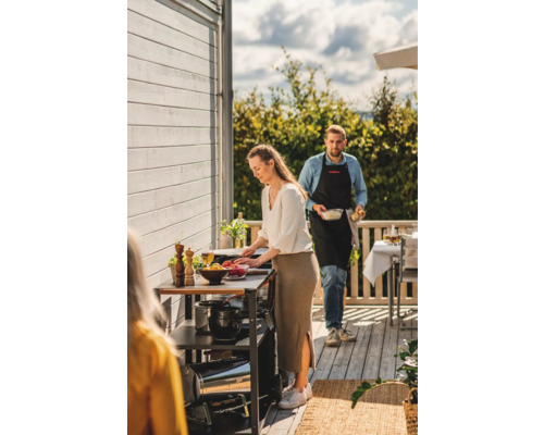 Personer som förbereder mat på en utomhusgrillstation.
