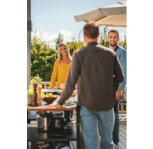 Social sammankomst vid grillning utomhus med grillvagn och parasoll.