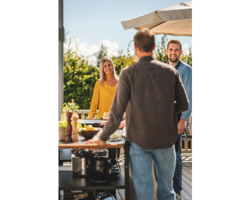 Social sammankomst vid grillning utomhus med grillvagn och parasoll.