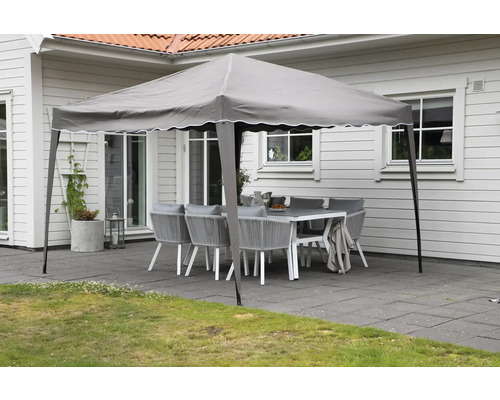 Trädgårdsscen med lusthus och sittgrupp på en terrass.