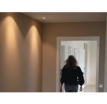 Hall med takspotlights och person som går genom en dörr