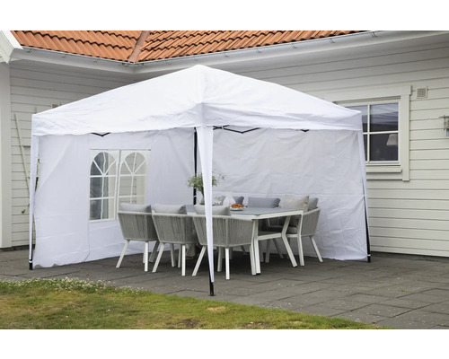 Vitt partytält med bord och stolar i trädgården