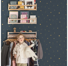 Barnrum med trähyllor på en stjärnprydd vägg och en pojke framför en klädställning