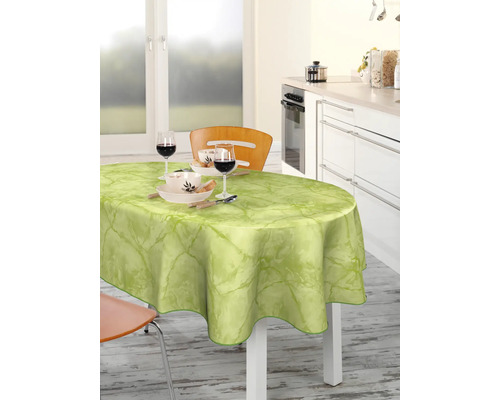 Matbord med ljusgrön vaxduk och porslin i ett ljust kök.