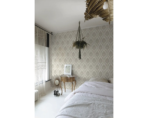 Sovrum med mönstrad tapet, säng, sängbord och krukväxt