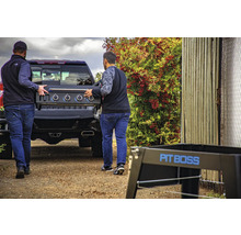 Två män lastar en Pit Boss-grill i en pickup.