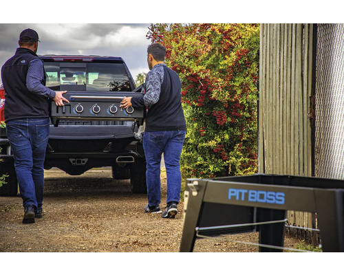 Två män lastar en Pit Boss-grill i en pickup.