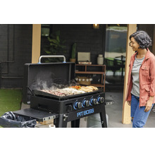 Pit Boss grill med mat och kvinna i bakgrunden