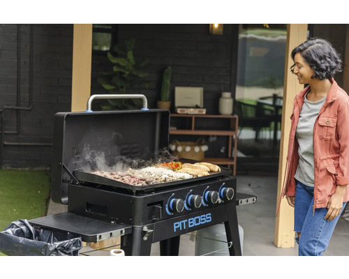 Pit Boss grill med mat och kvinna i bakgrunden