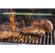 Flera biffar på en grill med öppen låga.