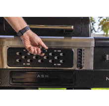 Detaljvy av en grill med en hand som ställer in temperaturen