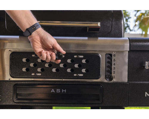Detaljvy av en grill med en hand som ställer in temperaturen