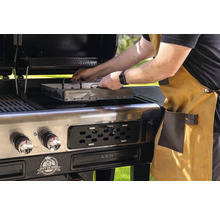 Man placerar en rökbox i en Pit Boss-grill.