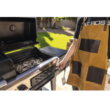 Grill med öppet lock, kol och person med grillförkläde