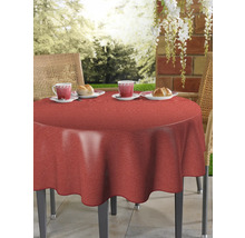 Runt bord med röd duk, dukat med koppar och bröd i trädgården