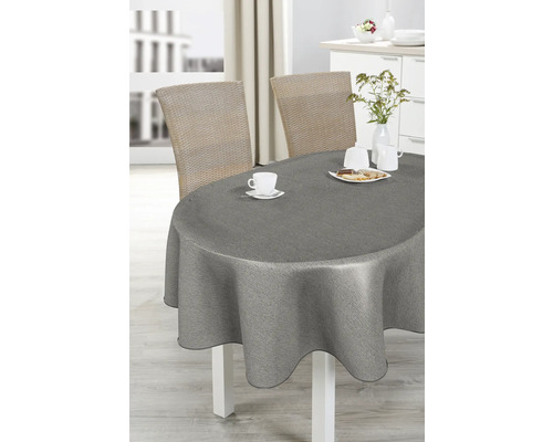 Matbord med grå duk, porslin och rottingstolar i ett ljust rum.