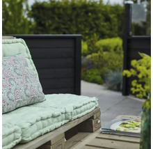 Scen med pallmöbler och en mönstrad kudde i trädgården