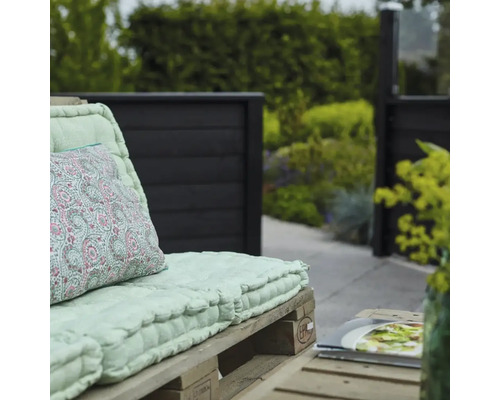 Scen med pallmöbler och en mönstrad kudde i trädgården