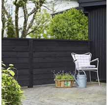 Trädgårdsscen med trästaket, trädgårdsstol, blomkorg och vattenkanna