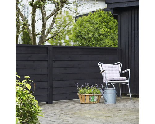 Trädgårdsscen med trästaket, stol, vattenkanna och växter