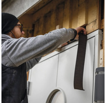 Hantverkare fäster tätningsband på en dörr för isolering.