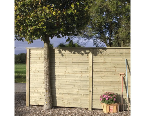 Trästaket med träd, blomkorg och trädgårdsredskap utomhus