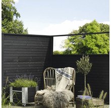 Trädgårdsscen med trästaket, rottingfåtölj, planteringslåda och dekorativa element för utomhusbruk