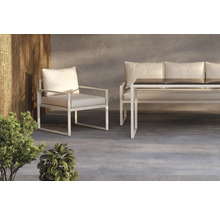 Trädgårdsmiljö med fåtölj, soffa och bord med glasskiva