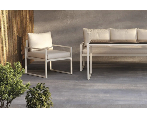 Trädgårdsmiljö med fåtölj, soffa och bord med glasskiva