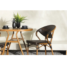 Miljöbild med trädgårdsbord i metall med två koppar, dekoration och en rottingstol