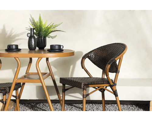 Miljöbild med trädgårdsbord i metall med två koppar, dekoration och en rottingstol