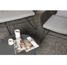 Scen med två fåtöljer med kuddar, ett runt bord, kopp, kanna och en tidning