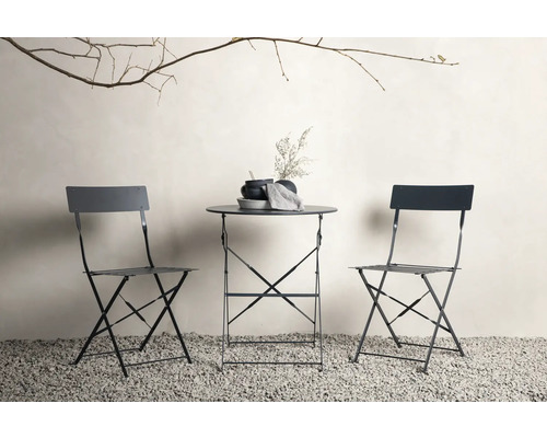 Trädgårdsscen med fällbord och två fällstolar på grusgolv