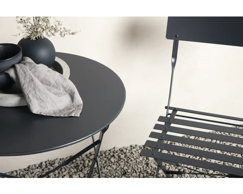 Trädgårdsscen med bistrobord, stol, porslin och duk utomhus.