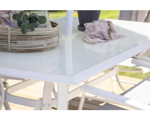 Detaljvy av ett trädgårdsbord med glasskiva, dekoration och parasollhållare