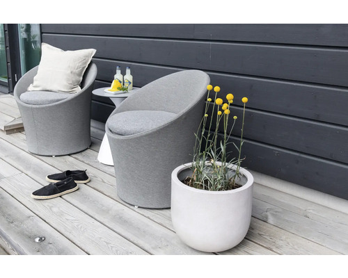 Miljöbild med två grå fåtöljer, ett sidobord, skor och en blomkruka med gula blommor på en träaltan