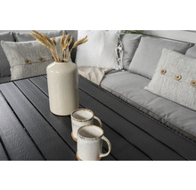 Trädgårdsbord med två koppar, en vas med veteax och kuddar på en bänk