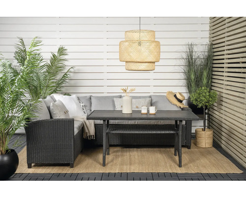 Uteplats med möbler, bestående av en sittgrupp med kuddar, ett bord med bänk, en hängande lampa och olika växter.