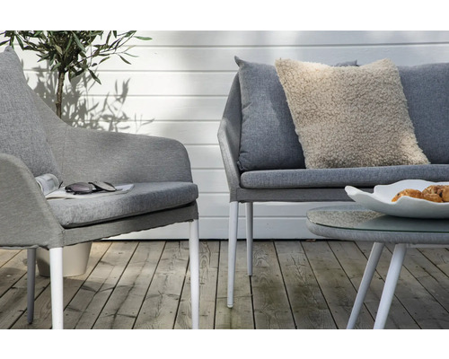 Scen med en grå fåtölj, en grå soffa, ett soffbord och en dekorativ kudde på en terrass