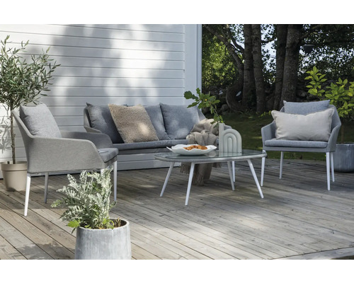 Uteplats med grå soffa, fåtöljer och ett bord med glasskiva för en mysig uteplats