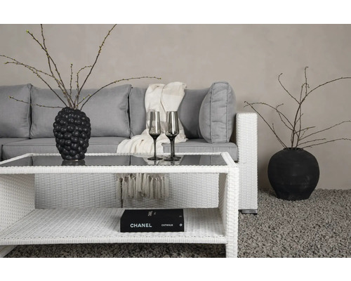 Vardagsrum med grå soffa, rottingbord, dekoration och två glas